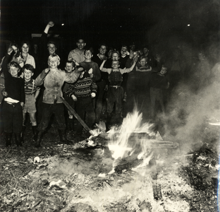 602859 Afbeelding van een groep kinderen rond de brandende resten van een oude woonwagen op het woonwagenkamp aan de ...
